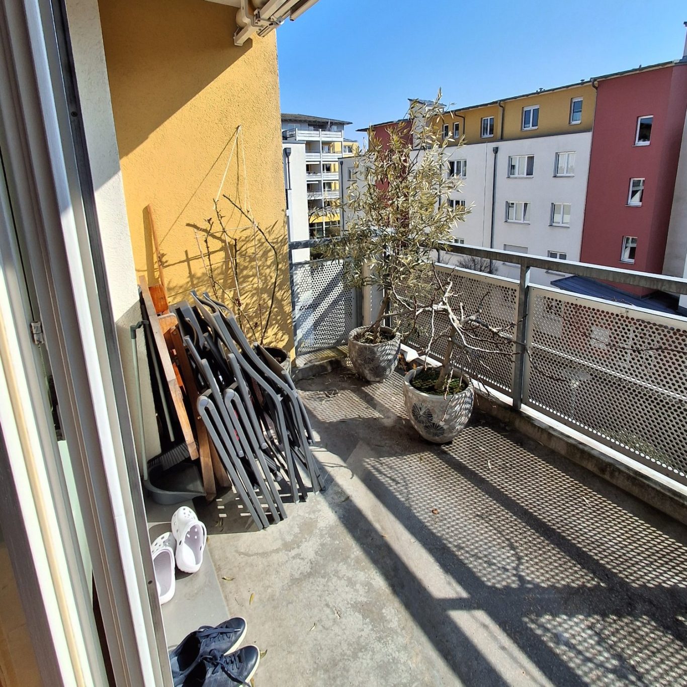 Balkon Balkon mit Pflanzen, Sicht auf Nachbargebäude, Sonnenschein und Krüppelholz.