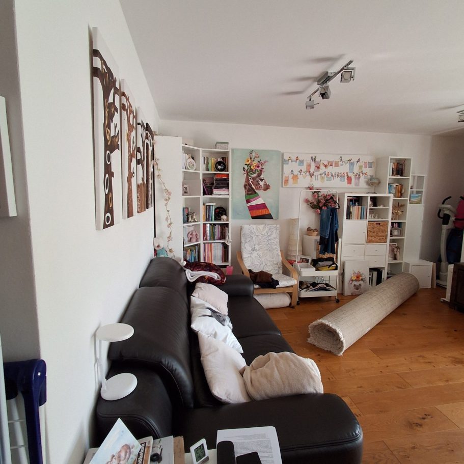 Wohnzimmer Geminierter Wohnraum mit einem schwarzen Sofa, Bücherregalen und unordentlichem Boden.